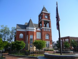 The historic Paulding County Courthouse located in Dallas GA with the American flag in the foreground against a bright blue sky